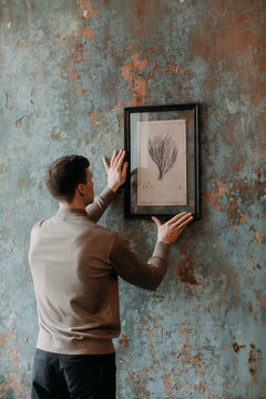 Man hanging painting on wall