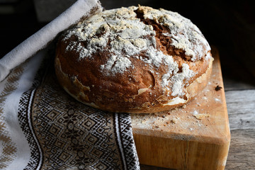 Homemade bread lies on a kitchen board in a folk, national napkin kitchen, on a wooden table.