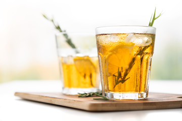 two glasses with lemonade and rosemary on a light background in high key