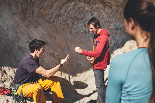 Two male climbers play stone, paper and scissors on rocky scenery