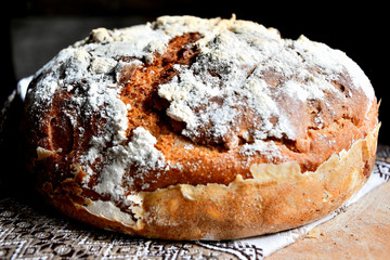 Homemade bread lies on a kitchen board in a folk, national napkin kitchen, on a wooden table.