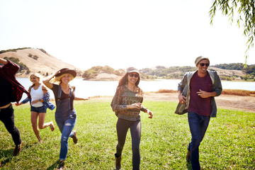 Group of Millennial friends running in nature