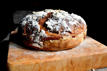 Homemade bread lies on the kitchen board in the kitchen, on a wooden table.