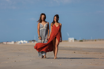 Complicity of two girls on the beach. Friends walking along the beach, laughing, having fun, lifestyle..