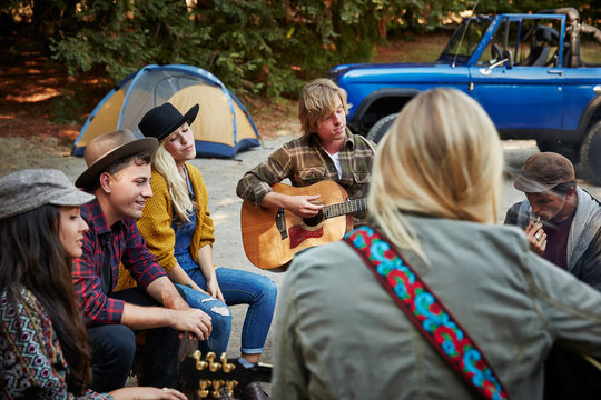 Group Of Friends Camping Around Fire Playing Music