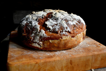 Homemade bread lies on the kitchen board in the kitchen, on a wooden table.