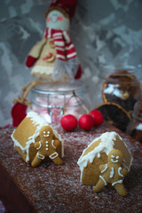 Traditional homemade gingerbread cookies on red rustic background with imitation snow,close up,Christmas concept,gingerbread house and gingerbread man