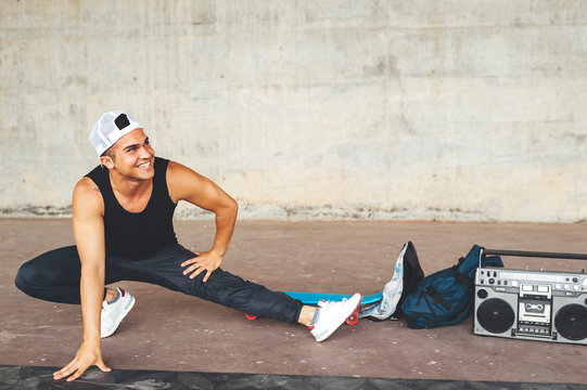 Portrait of young smiling hispanic man break dancer stretching after performing a dance in the street