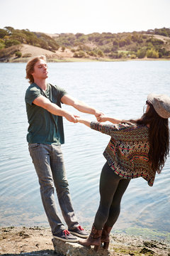 Man and woman holding hands and balancing on rock