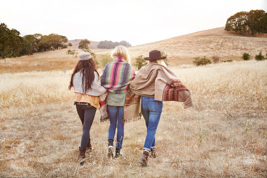 Three women friends walking in open field in nature
