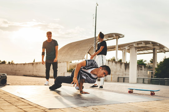 Mixed race group of young break dancers performing a dance in the street at sunset