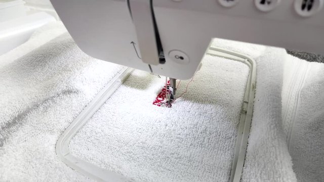 Embroidery on the sewing machine, red thread. The fabric in the embroidery frame of the sewing machine. 
