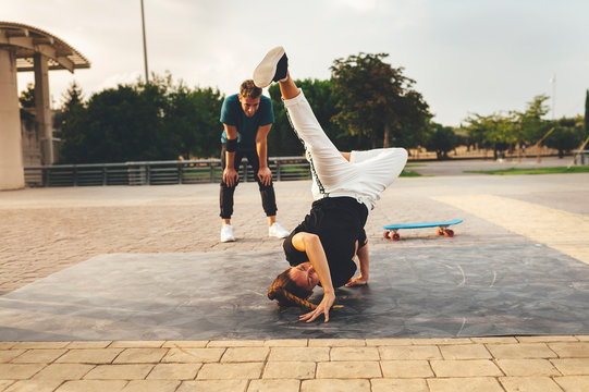 Young woman performing a dance pose at sunset in the street surrounded by friends