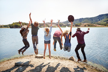 Group of friends jumping in the air at lake