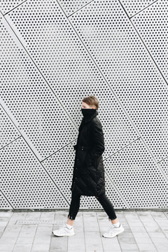 Woman in black coat against metal wall