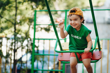 beautiful little boy spinning on a summer swing with space for text