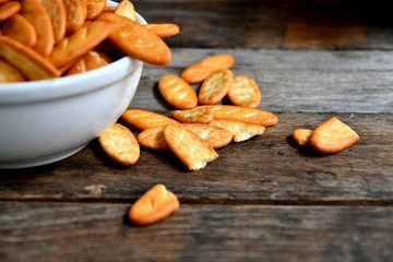 Cracker cookies in a white ceramic bowl on a wooden table.Cracker cookies in a white ceramic bowl on a wooden table.