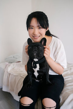 Chinese felame model sitting on the bed with friench bulldog