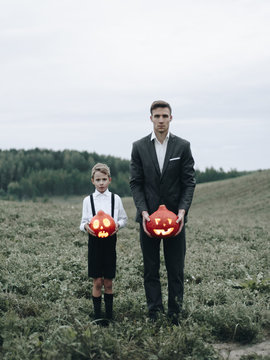 Man and boy standing in meadow with pumpkins