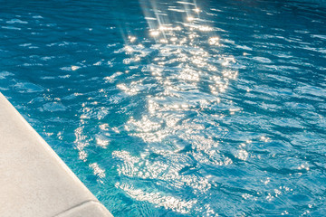 closeup of swimingpool with clean blue water and sun rays summer background