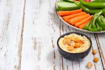 Hummus platter with assorted snacks. Hummus in bowl, vegetables sticks, chickpeas, olives. Plate with Middle Eastern/Mediterranean meze. Party/finger food. Top view. Vegetables, hummus dip,copy space