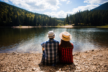 Obraz premium Travelers couple admire view of mountain lake. Travel and active life concept. Adventure and travel in mountains