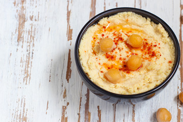 Hummus platter with assorted snacks. Hummus in bowl, vegetables sticks, chickpeas, olives. Plate with Middle Eastern/Mediterranean meze. Party/finger food. Top view. Vegetables, hummus dip,copy space