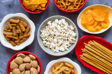 Variety of unhealthy snacks overhead shot laying on the table on different ceramic plates