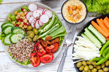 Hummus platter with assorted snacks. Hummus in bowl, vegetables sticks, chickpeas, olives. Plate with Middle Eastern/Mediterranean meze. Party/finger food. Top view. Vegetables, hummus dip,copy space