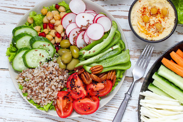 Hummus platter with assorted snacks. Hummus in bowl, vegetables sticks, chickpeas, olives. Plate with Middle Eastern/Mediterranean meze. Party/finger food. Top view. Vegetables, hummus dip,copy space