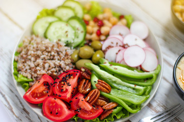 Hummus platter with assorted snacks. Hummus in bowl, vegetables sticks, chickpeas, olives. Plate with Middle Eastern/Mediterranean meze. Party/finger food. Top view. Vegetables, hummus dip,copy space