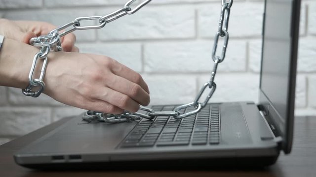 Internet chained people. Women's hands are chained to a laptop. Internet addiction.