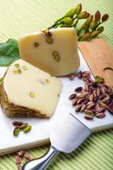 Italian provolone or provola cheese made in Sicily with tasty green Bronte pistachio nuts served on white marble plate close up
