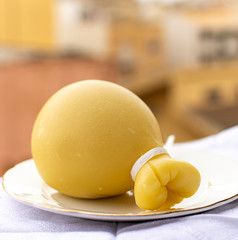 Italian provolone caciocavallo aged cheese in teardrop form with yellow houises in old Italian town on background