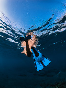 girl in a blue swimsuit swims in flippers and a mask and looks at corals and reefs with fish