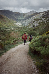 Men couple with backpack walking on a mountain path