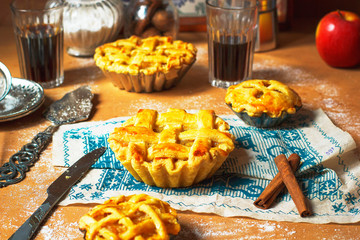 Mini homemade apple pies on rustic background with coffee,cinnamon sticks,apples,vintage towel