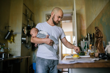 Father cooking and carrying his baby