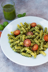 Italian pasta fusilli with green pesto sauce and Parmesan. Vertical orientation.
