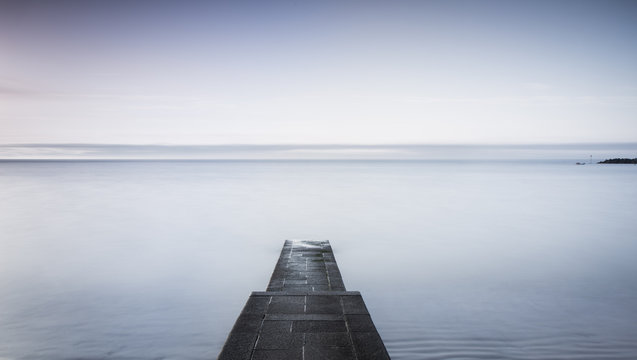 Fototapeta A stone jetty jutting into a calm sea