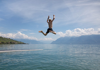A boy leaping from a diving board over a lake