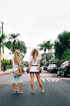 Skating in Venice - Two Young Anonymous Young Women Standing in Street With Skateboards