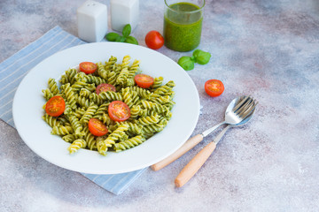 Italian pasta fusilli with green pesto sauce and Parmesan. Horizontal orientation.