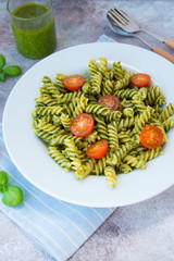 Italian pasta fusilli with green pesto sauce and Parmesan. Vertical orientation.