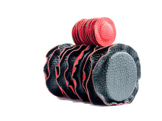 Isolated circular magnets lined in red and black leather of different sizes lying on top of each...
