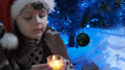 Christmas warmth. Cute little girl with a burning candle on Christmas night.