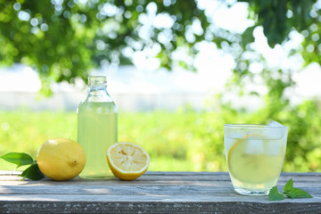 Glasses of lemon juice on a wooden table, summer set, outdoor greed blured background,boke.Water detox