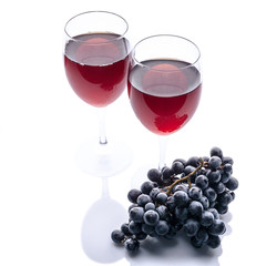 Red wine in glasses and a bunch of black grapes on a white background. Isolated composition