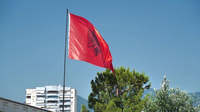 National Flag of Republic of Albania in Tirana city. Red flag with silhouetted black double-headed eagle in center. Tirana - capital and largest city of Republic of Albania