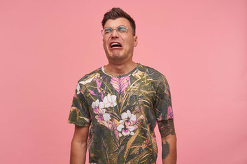 Close up of upset distressed young guy with closed eyes, crying a river over pink background,...